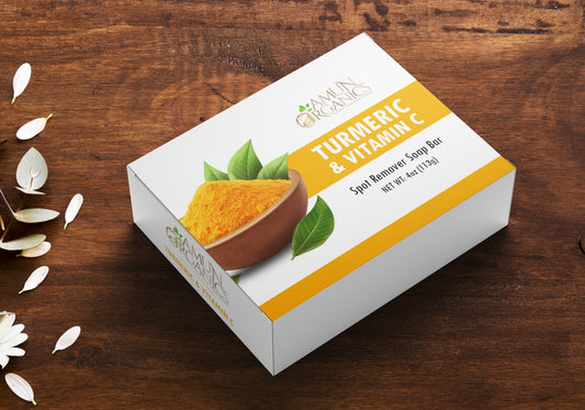 Box of Turmeric & Vitamin C Spot Remove Soap Bar on a wooden surface with turmeric powder and leaves.
