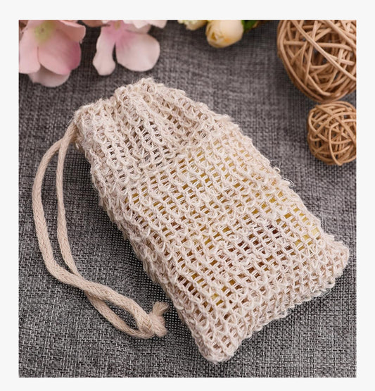 Woven soap bag on a textured surface with flowers and twine in the background