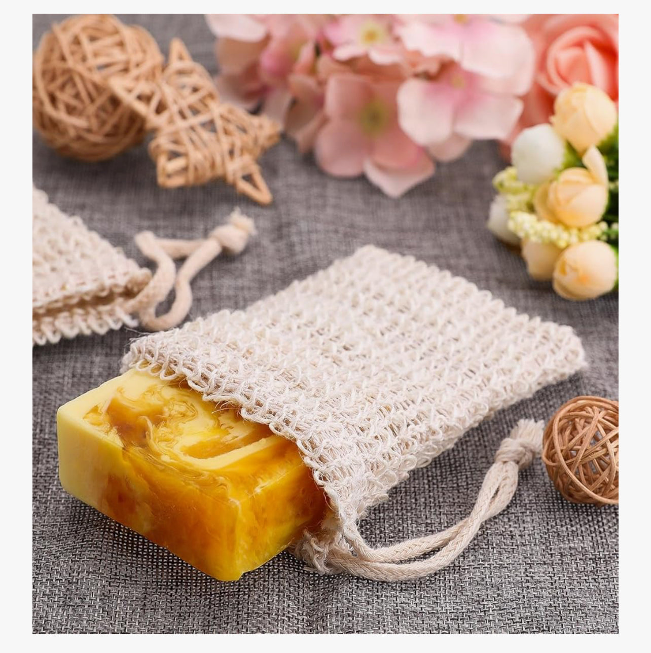 Yellow soap bar in a mesh bag on a textured surface with decorative elements.